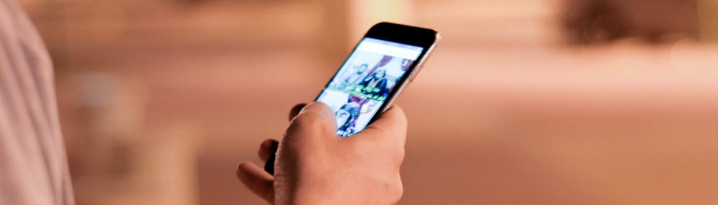 man holding and scrolling a black smartphone